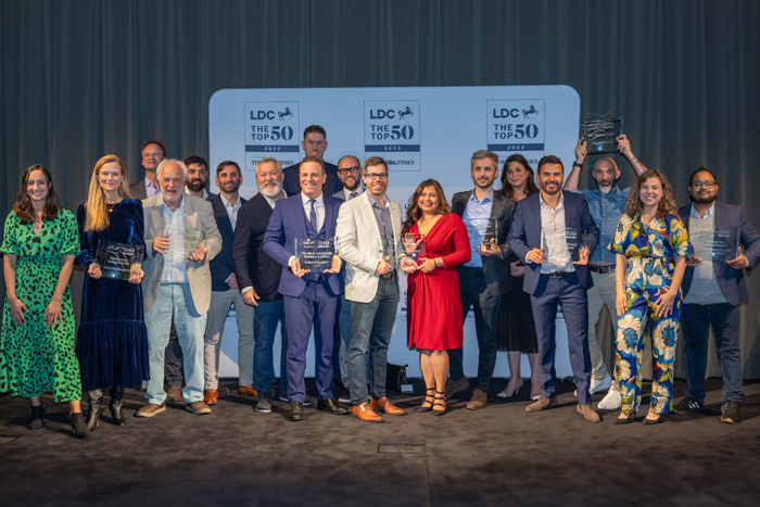 Group of professionals at 'The Top 50 Awards LDC 2023', holding awards on stage.