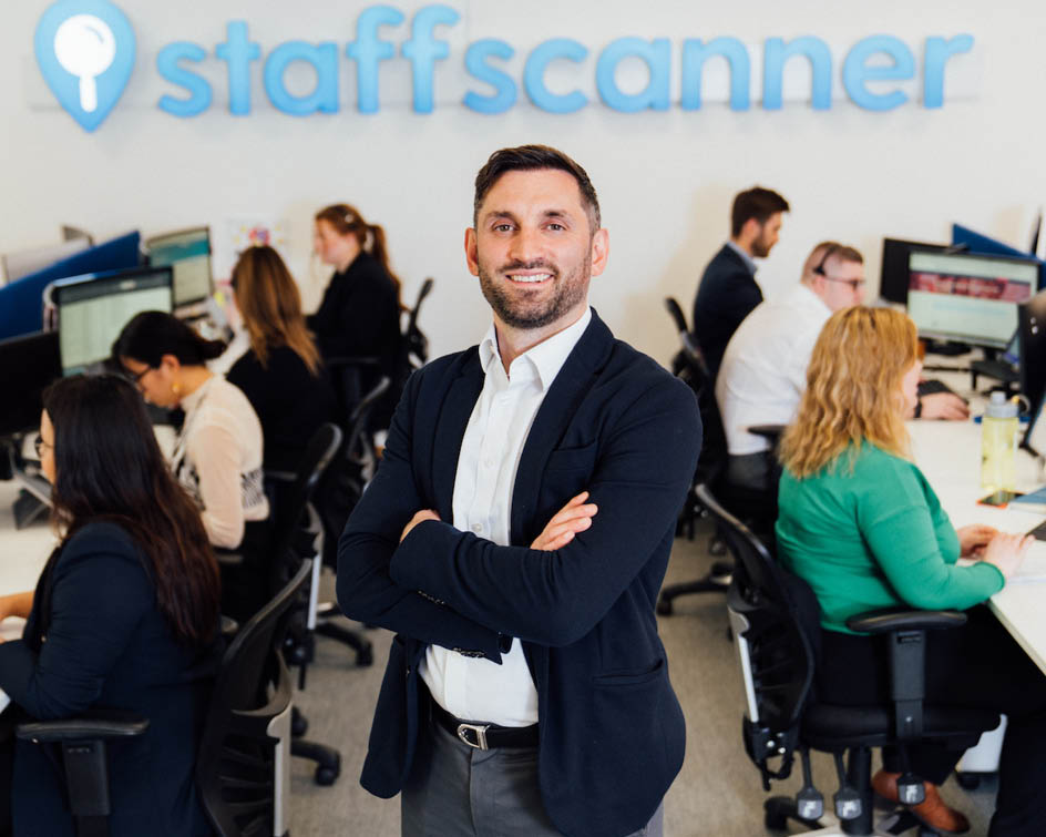 Nomad Najafian standing with arms folded looking happy in the StaffScanner offices.