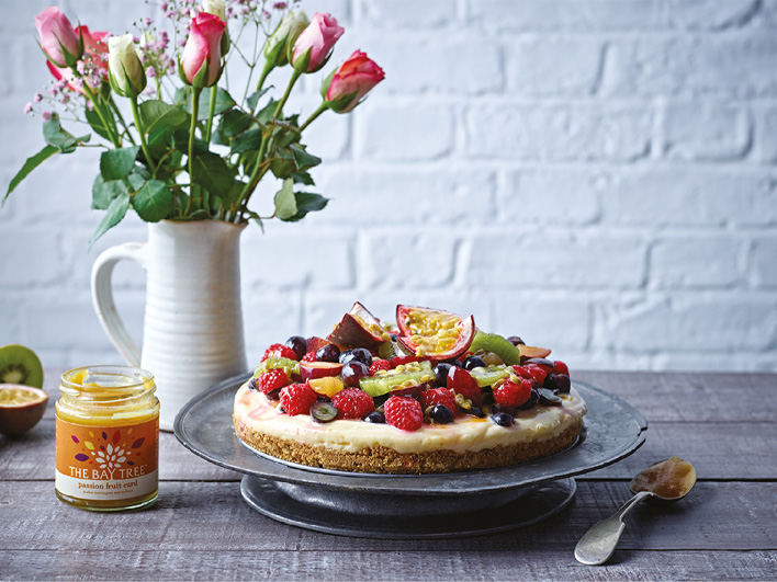 'Bramble Foods' passion fruit cake with a mix of vibrant fruits and a jar of passion fruit curd sitting next to it.