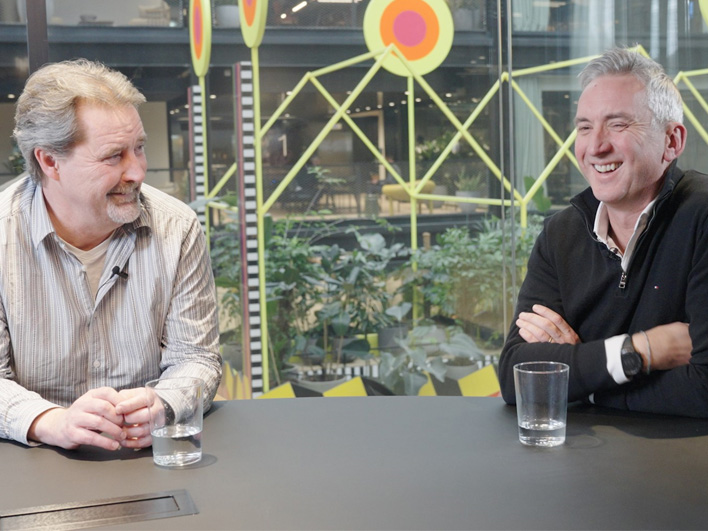 Kerv founders Alastair Mills and Mike conversing at an office table.