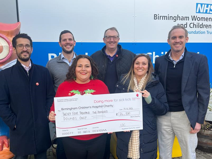 Five smiling people presenting a large check from LDC to the Birmingham Children's Hospital Charity for £24,700.